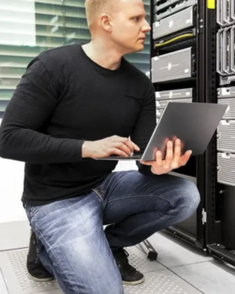 IT-konsultti työskentelee kannettavalla palvelinkaappien äärellä