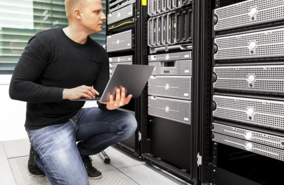 IT-konsultti työskentelee kannettavalla palvelinkaappien äärellä